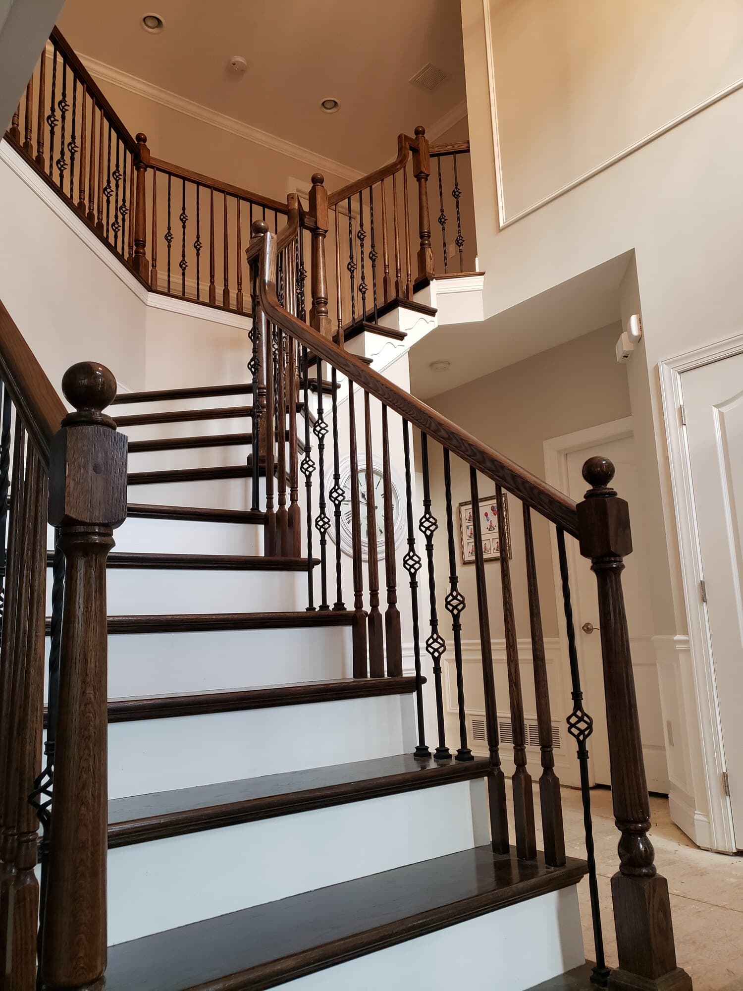 Before the remodel — dated dark oak handrail and ornate basket-twist iron over the switchback flight
