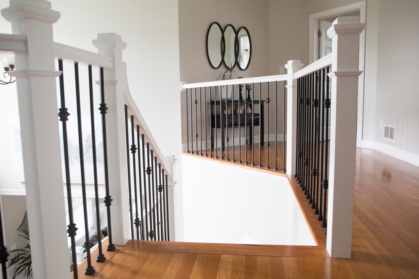 Satin-black iron balusters and white newels on a finished foyer railing — a Lehigh Valley install