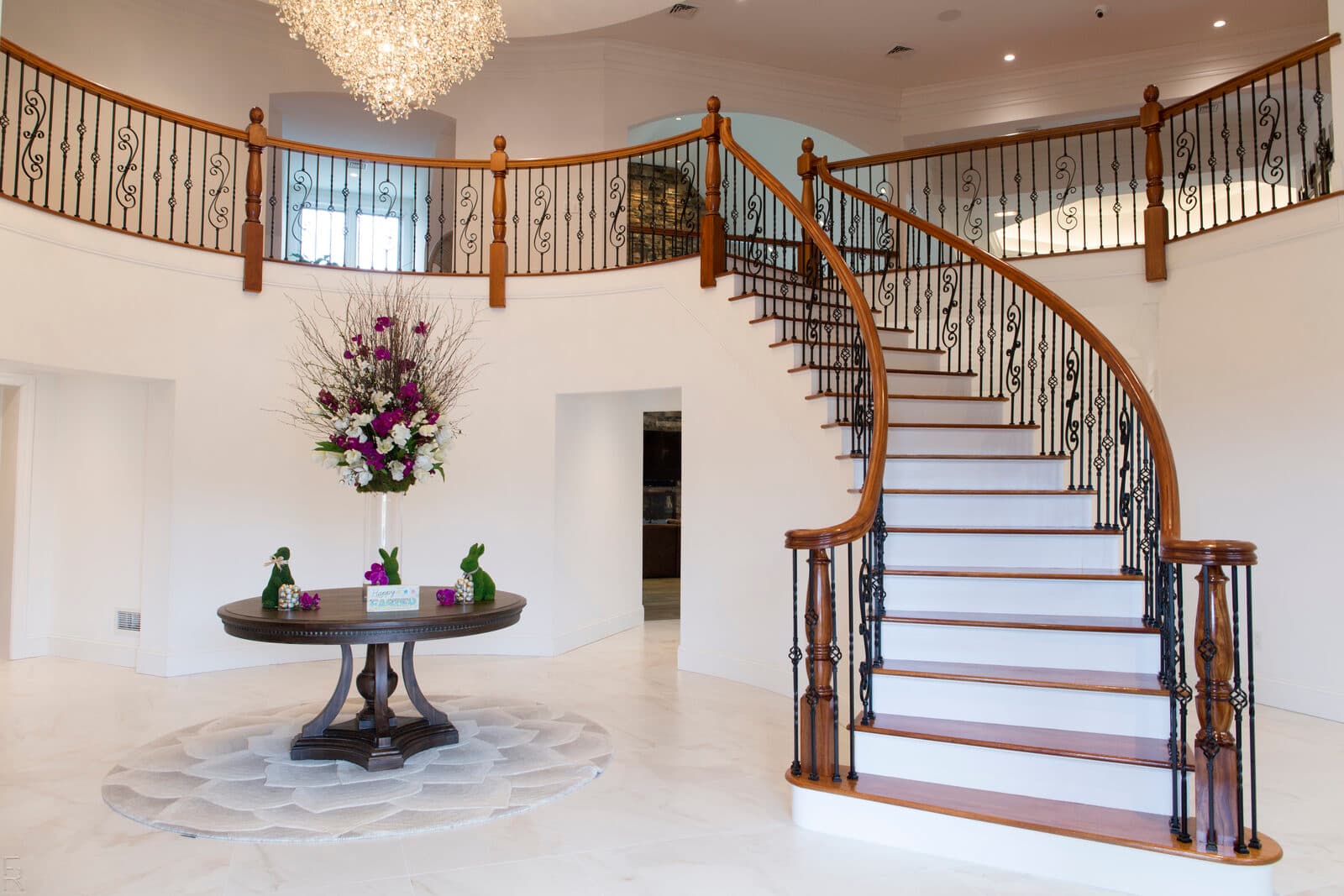 Grand sweeping curved staircase with warm bronze iron and an over-the-post handrail in a Lehigh Valley foyer