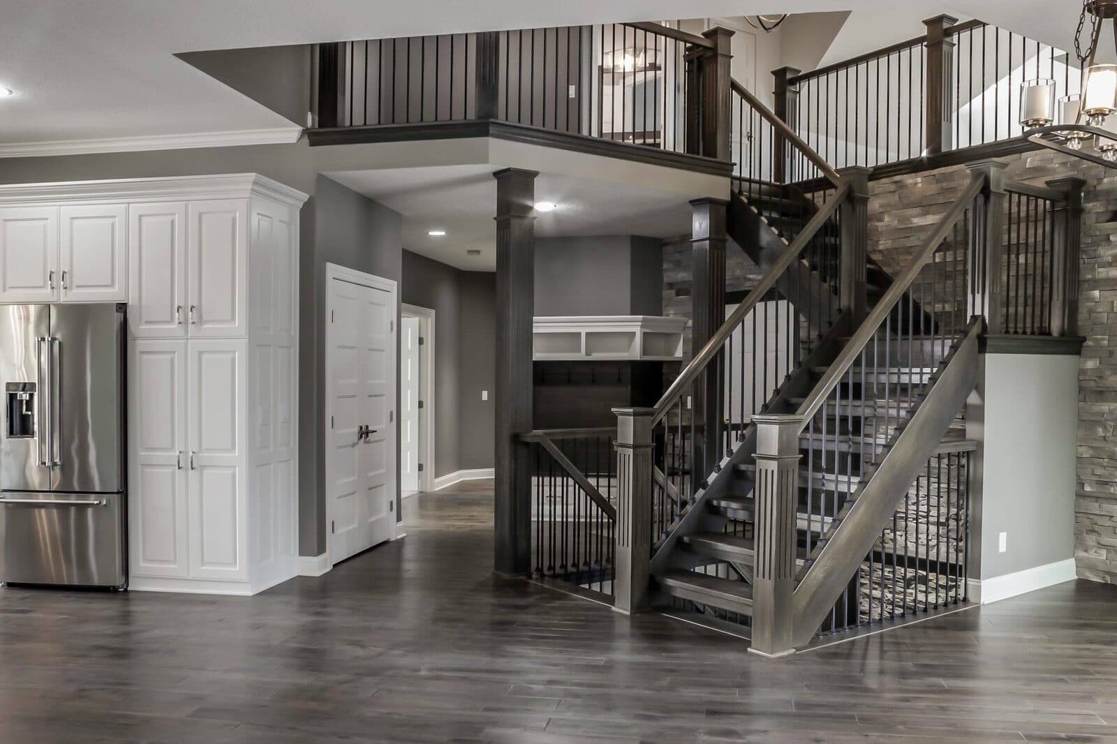 Modern multi-story stair with code-compliant cable railing and stone wall — apartment-building stair-tower aesthetic in a Lehigh Valley new-construction property