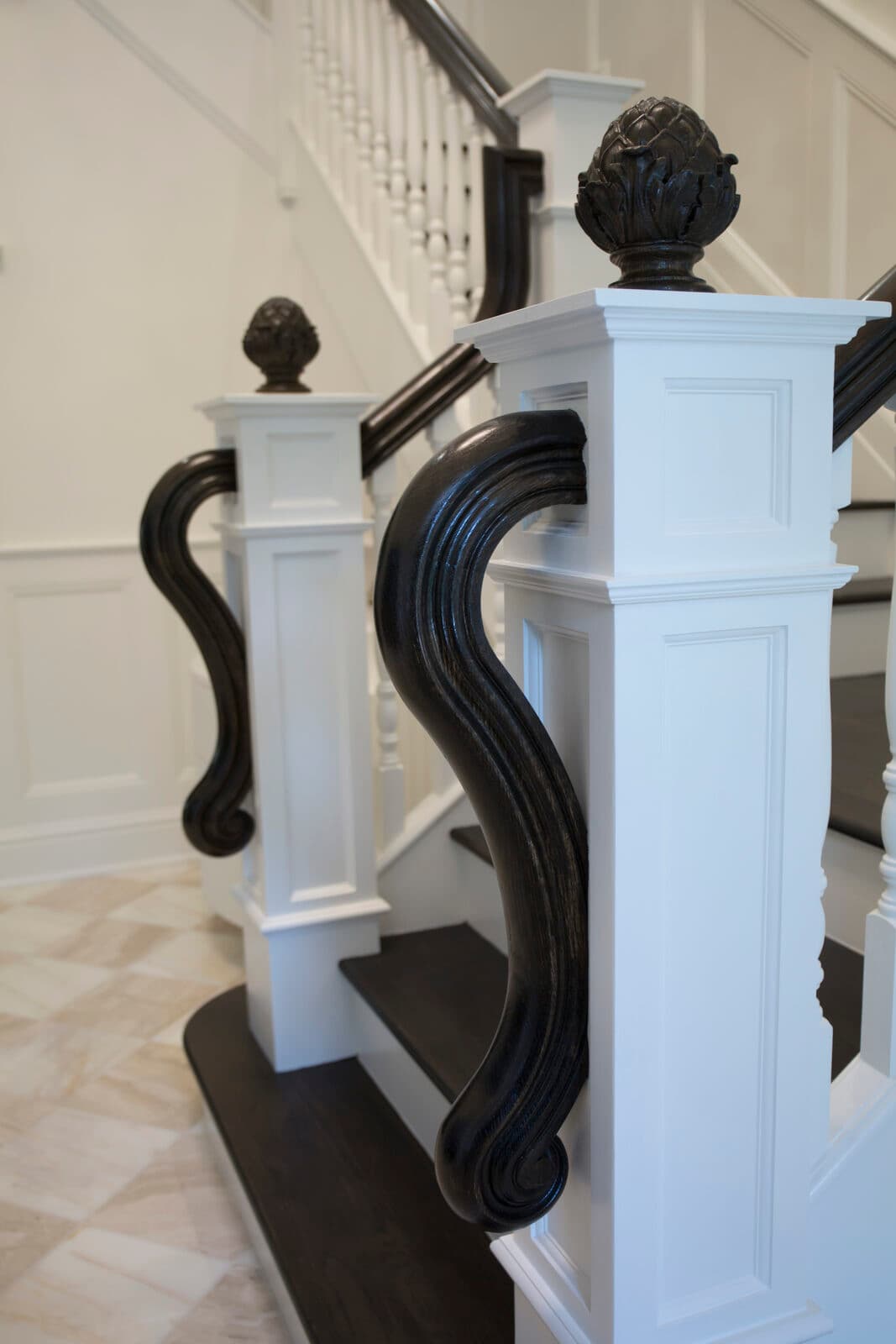 Carved newel post and finial detail on a traditional walnut staircase from the Snyder shop