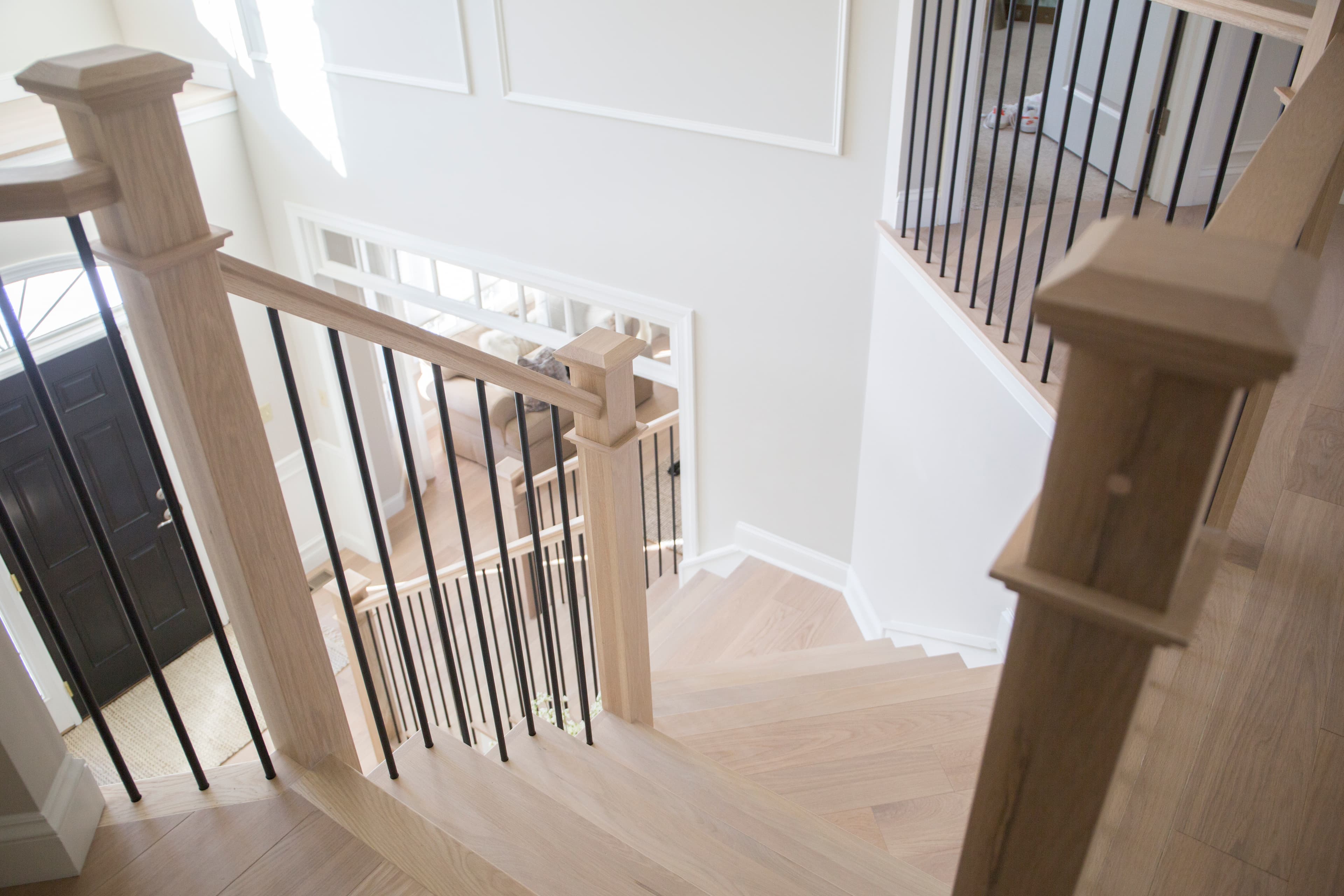 White-oak box newel posts with square iron balusters on a stair overlooking a foyer