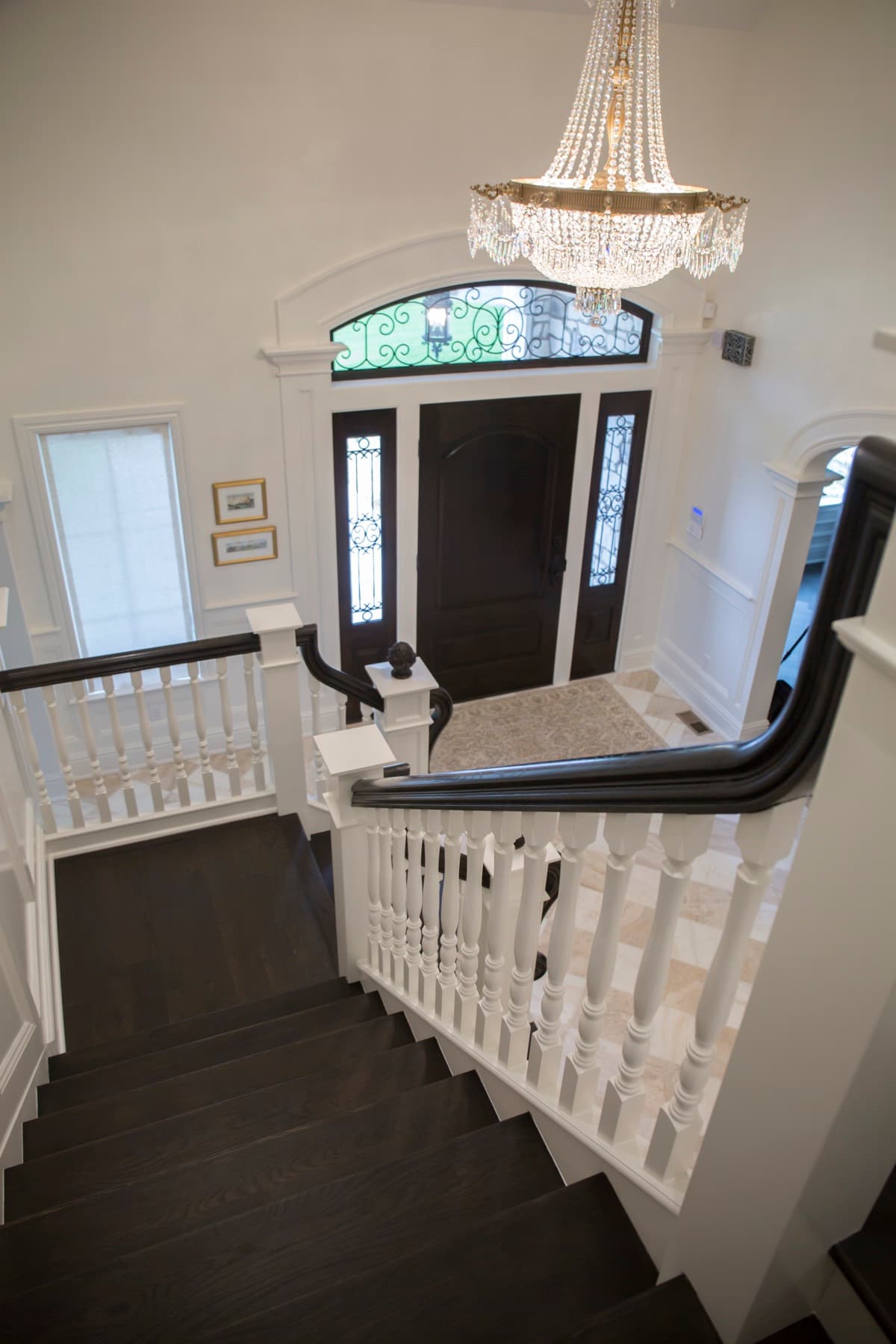 Grand foyer stair with dark treads, white balusters, and a crystal chandelier — Lehigh Valley custom stair