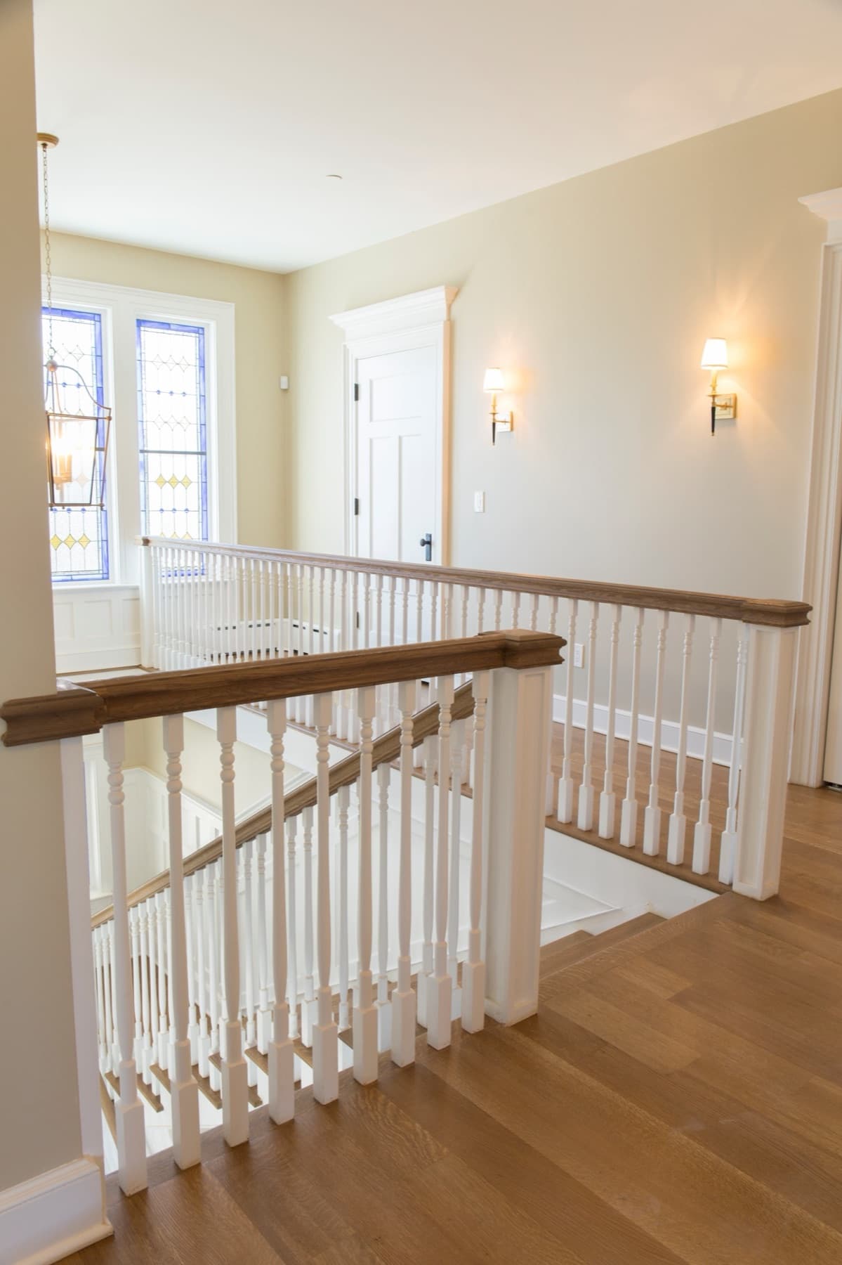 Faucett landing with turned white balusters, stained oak handrail, and oak floors