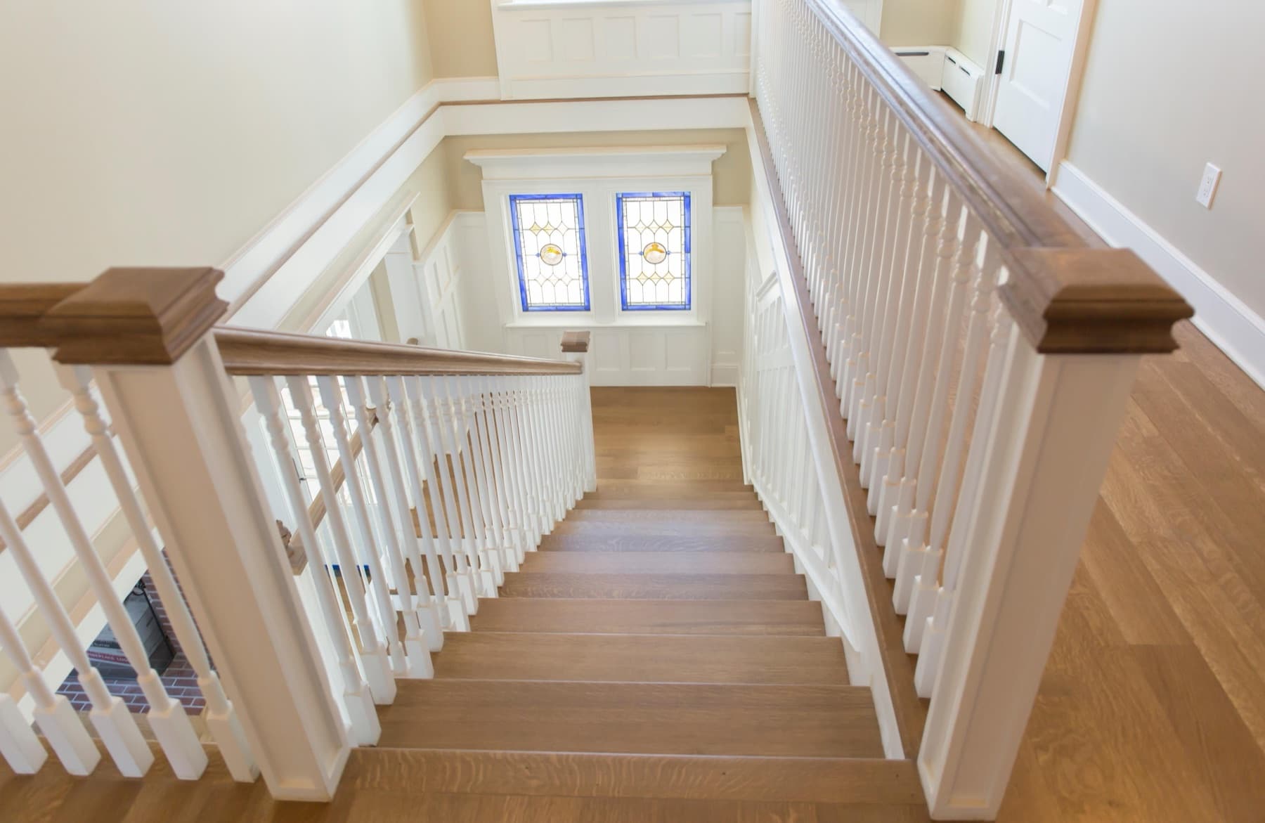 Oak stair with white balusters and a stained-glass window — Faucett period restoration