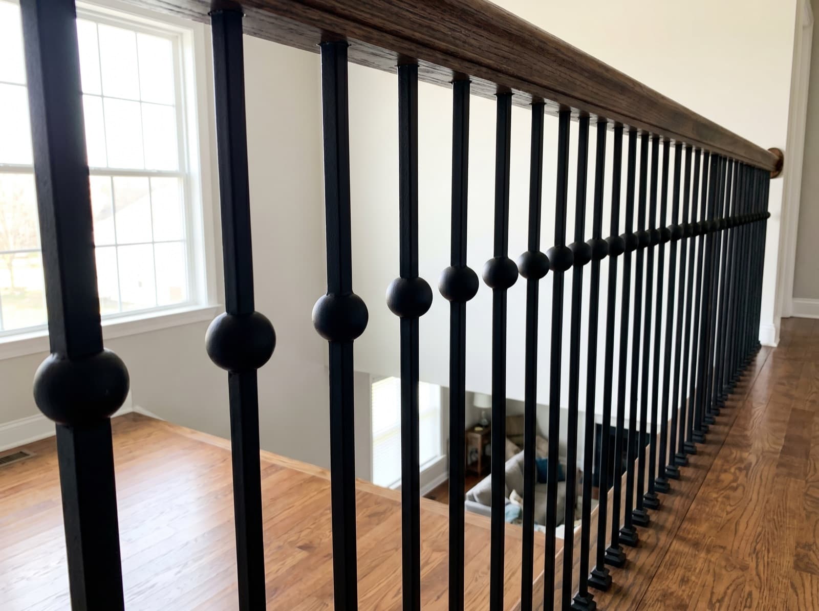 Installed satin-black iron balcony run with code-compliant spacing along a second-floor overlook