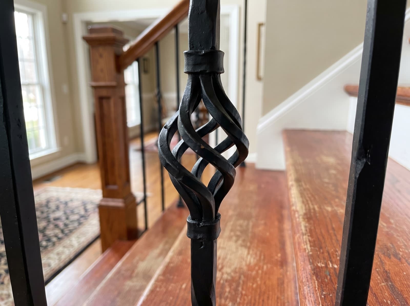 Installed satin-black iron baluster with basket-weave detail at mid-height