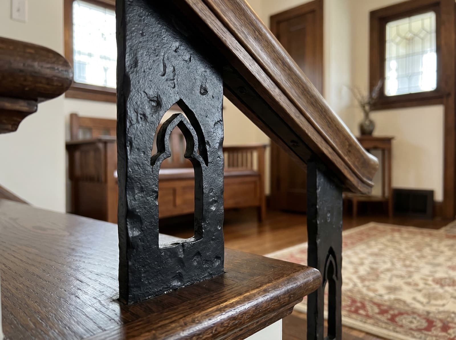 Installed satin-black iron newel with Gothic pointed-arch cutout detail