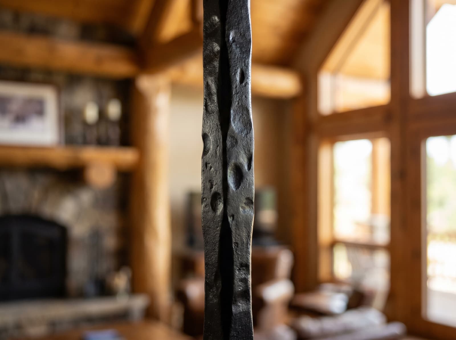 Installed satin-black iron baluster with hammered-texture face in a lodge interior