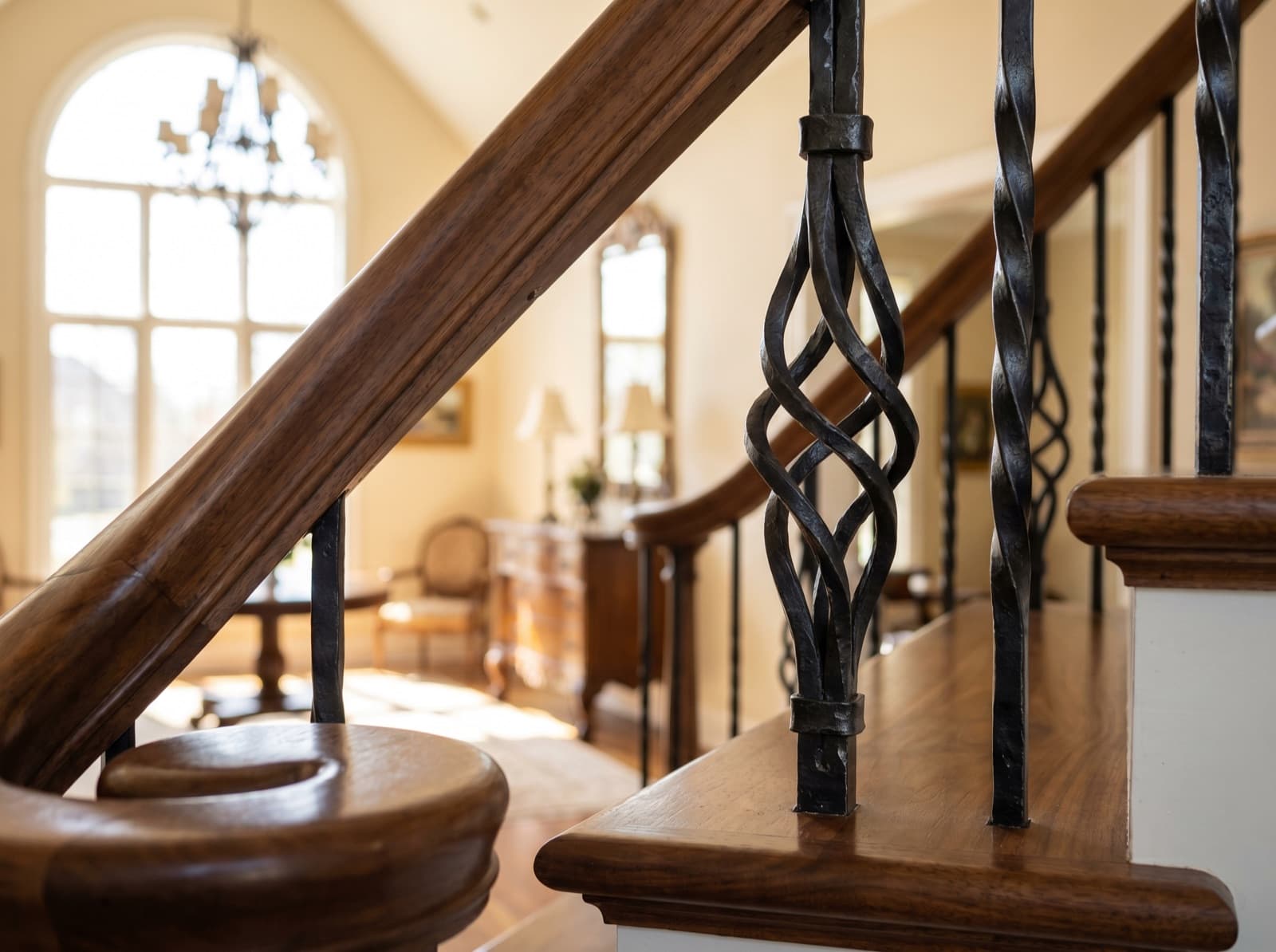 Installed satin-black iron balusters with flowing ribbon-twist detail in a curved foyer