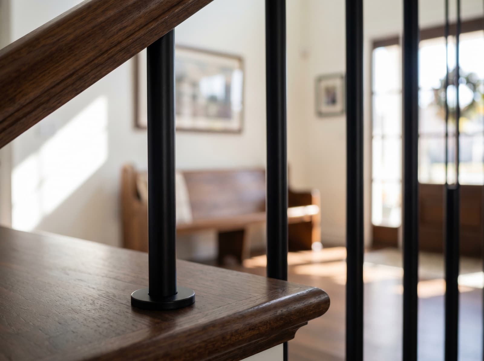 Installed plain round-stock satin-black iron post on a wood newel cap