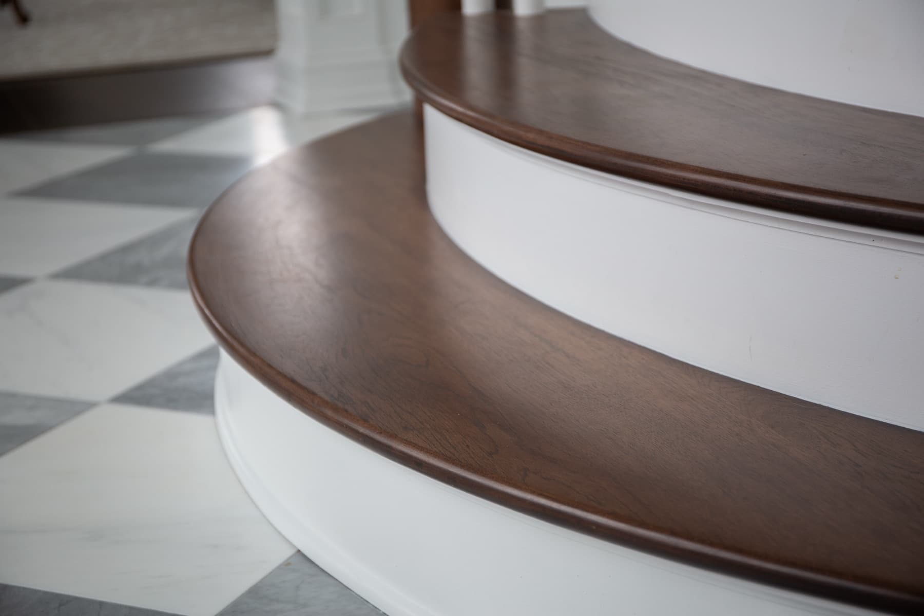 Macro of curved walnut bullnose treads over marble — Rambo residence craft detail
