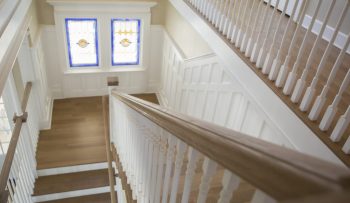 Wooden handrail and and staircase leading down to front door.